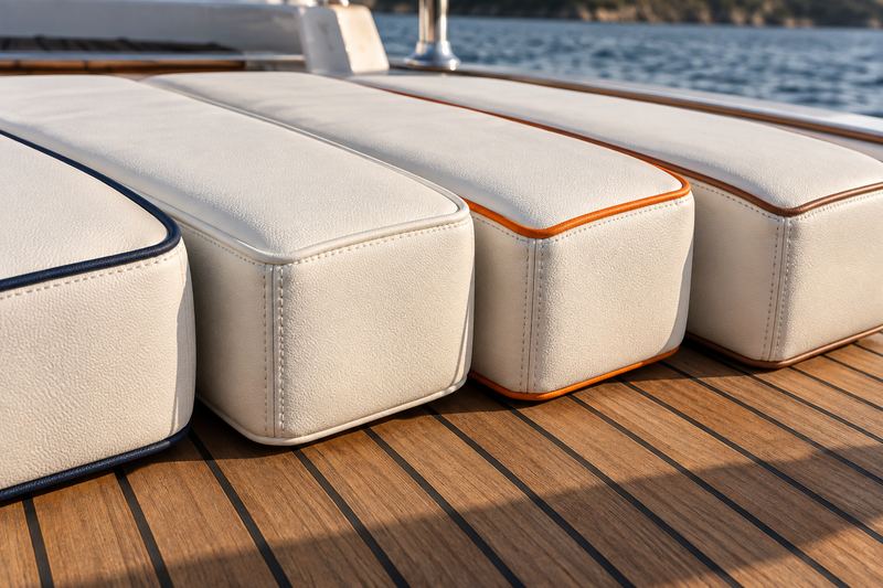 Four cushion corners with navy, white, orange and cognac piping on white vinyl