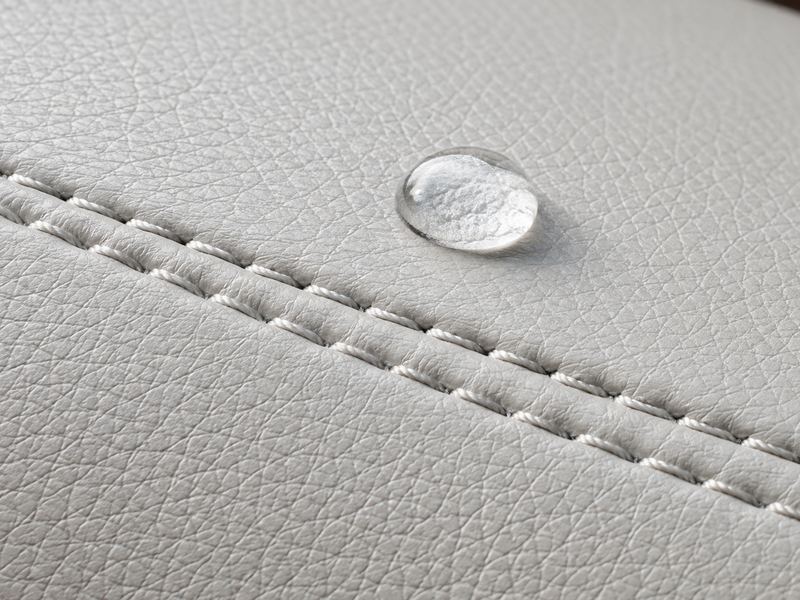 Close-up of white marine vinyl grain with a double-needle seam and a water bead