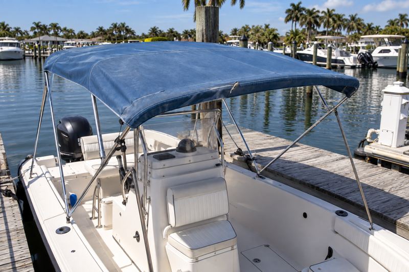 25 ft center console with a sun-faded, sagging light blue bimini and a torn seam
