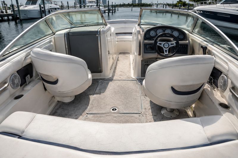 Cockpit floor of a 28 ft bowrider with worn, stained beige carpet frayed at the edges