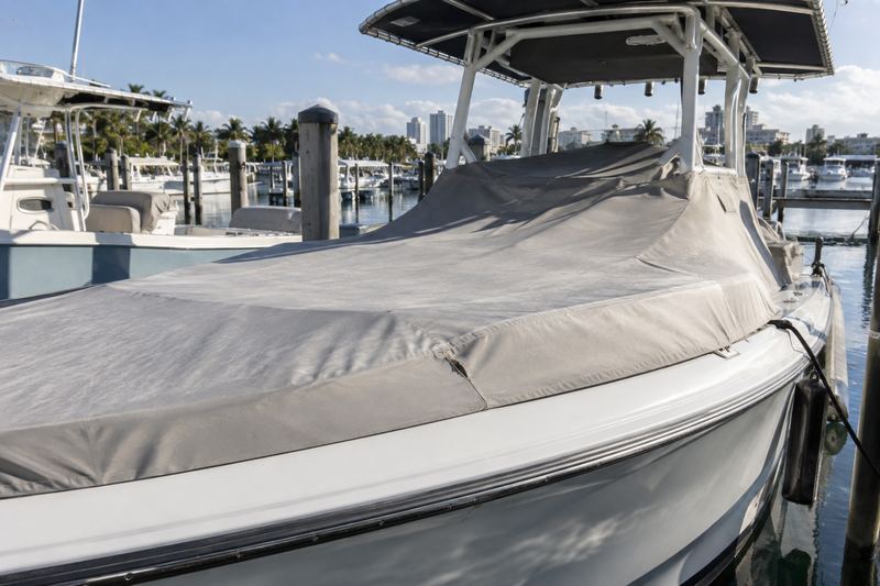 32 ft center console on a lift under a ragged blue tarp tied with ropes