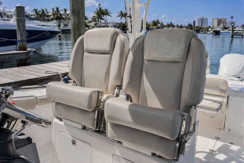 Twin helm seats with bolsters in cracked, yellowed white and blue striped vinyl