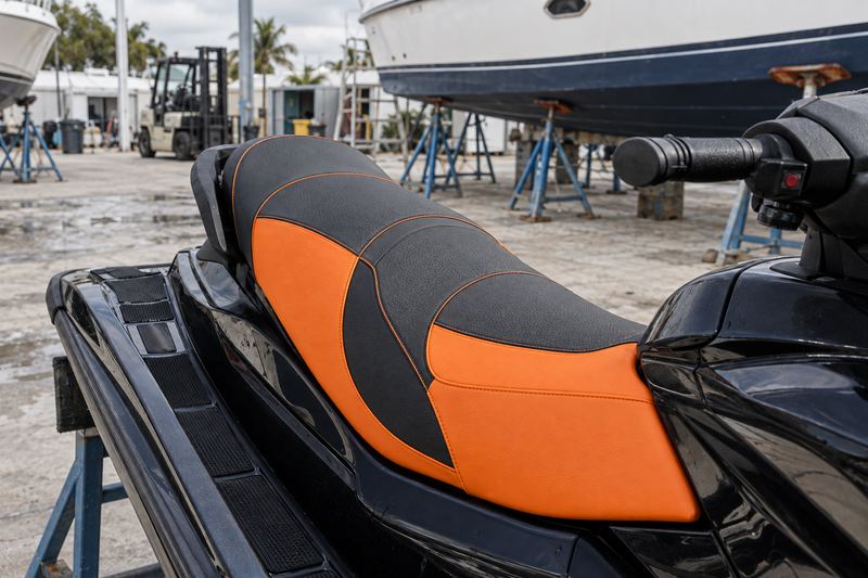 The same seat recovered in black and orange two-tone grip vinyl with white stitching