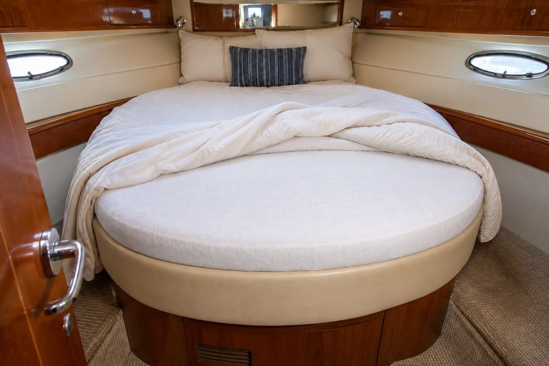 The same berth with a new custom-shaped mattress in fitted white linen and a navy throw