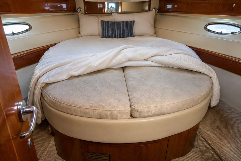 Forward berth of a 45 ft motor yacht with a thin sagging mattress and faded bedding