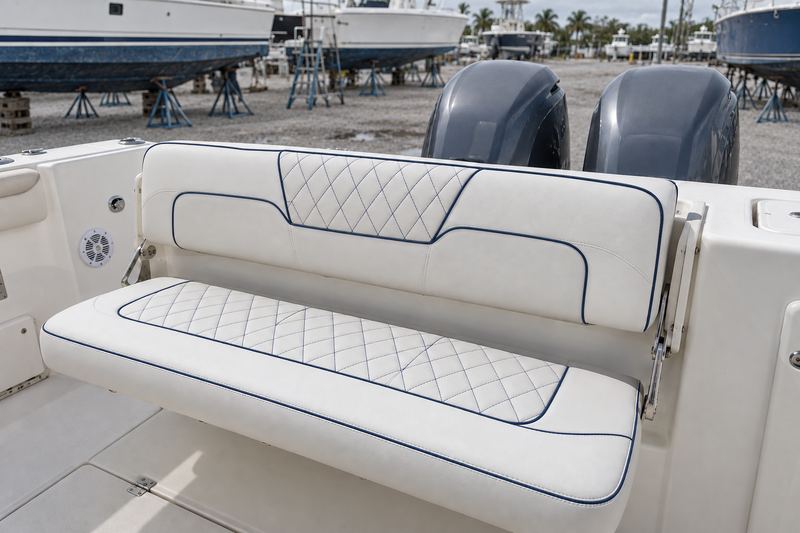 The same bench seat recovered in white marine vinyl with navy diamond stitching and navy piping